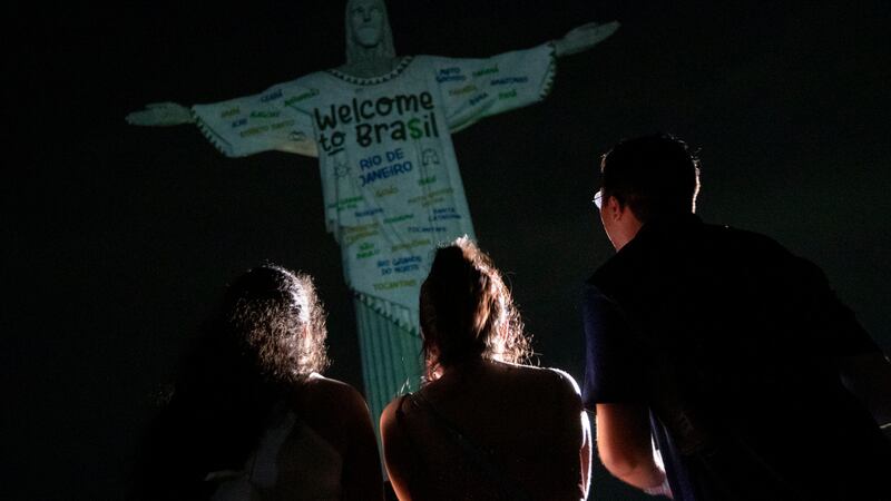 Fans look up at the Christ the Redeemer statue that is illuminated with a welcome message to...